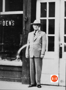 Mr. John M. Harden standing in front of his Harden's Hardware Com, in ca. 1938.