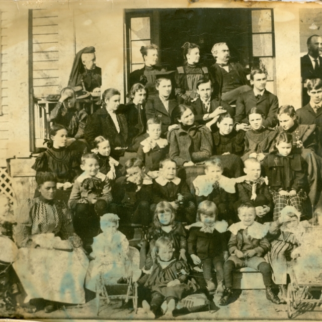 Members of the Adams and Crawford family gather at the turn of the century. Dr. and Mrs. Crawford are seated in the doorway of the home.