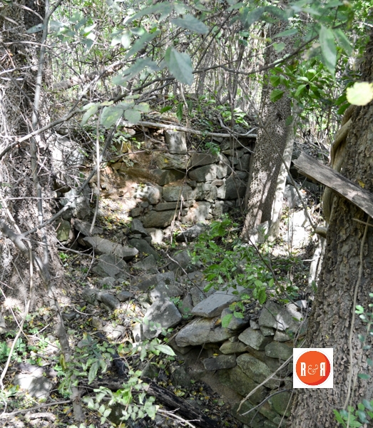 Remains of the dry stacked rock foundation and cellar.
